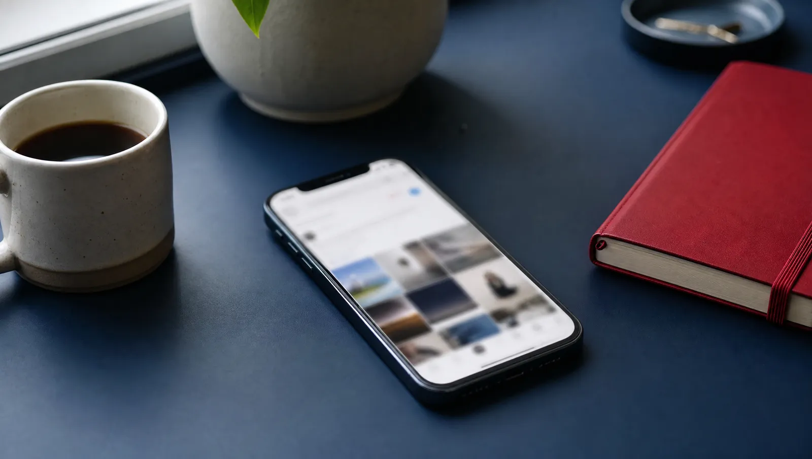 A smartphone lying on a desk with a blurred social feed on its screen
